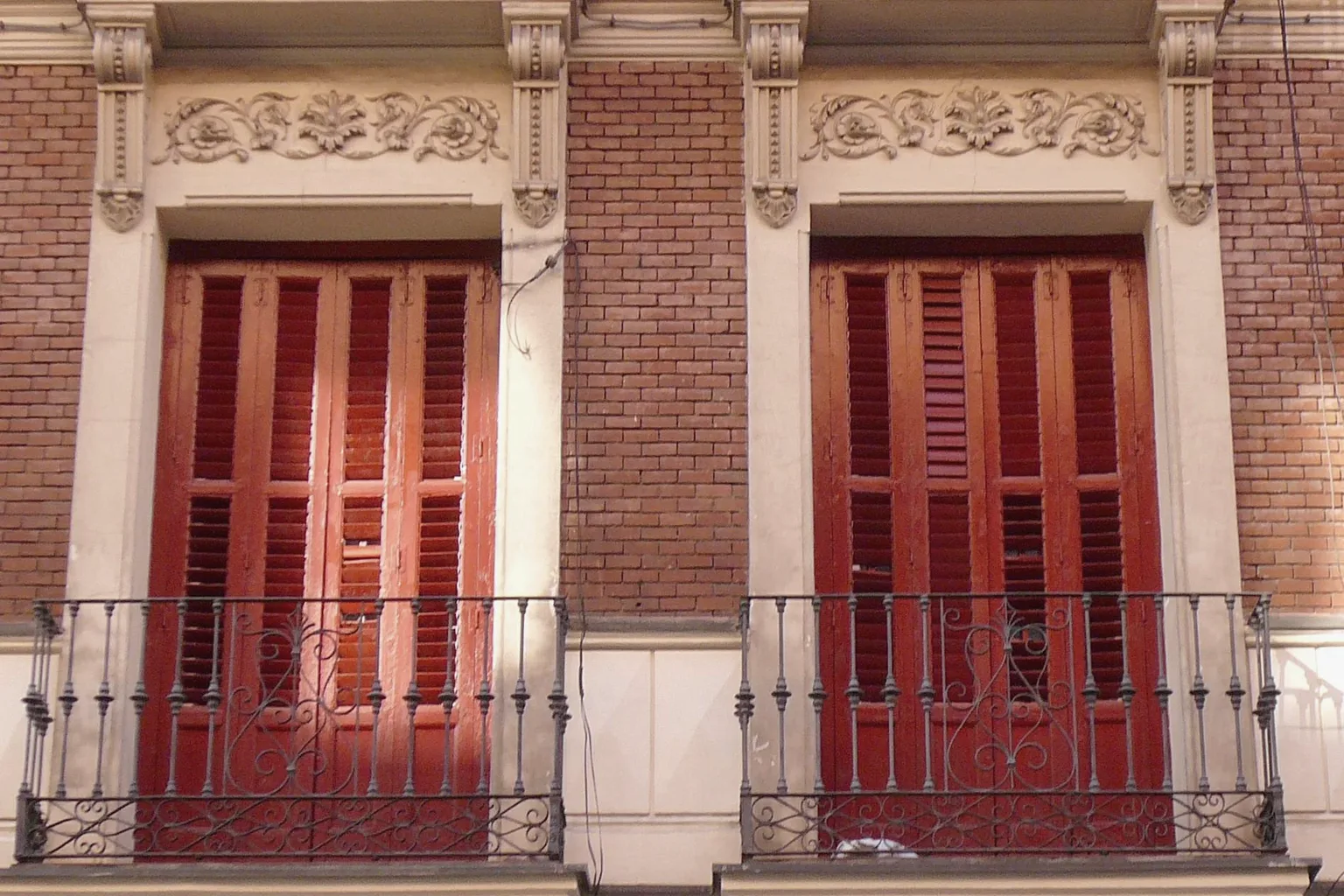 Wrought-iron balconies and wooden shutters on a period Madrid building.